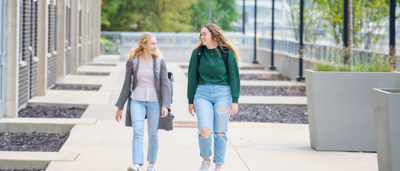 Students walking on a sidewalk in front of Mayflower Hall