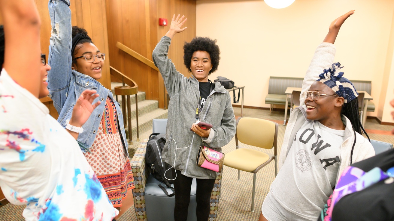 Students standing and raising their hands in a circle